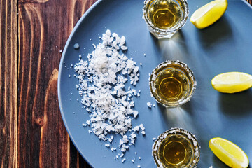 Tequila shot with lime and sea salt on grey plate