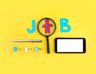 Minimalist job searching concept. Magnifier with job word, smaptphone and stationery on yellow background. Surf internet for recruitment or online freelance. Copyspace.