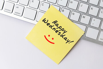 Happy Wednesday text on yellow paper note stick on computer keyboard