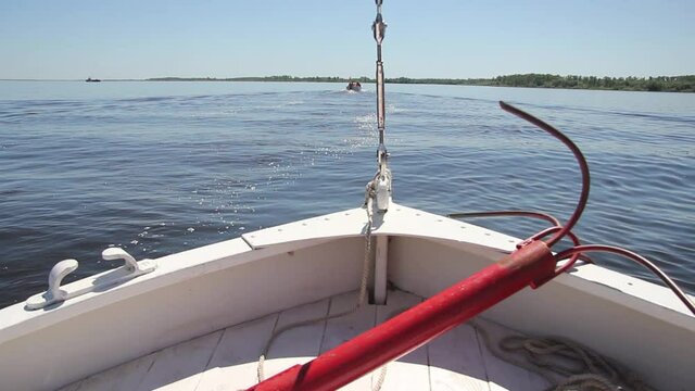 A red metal ship anchor lies on the deck of a white boat sailing the river on a summer clear day. High quality FullHD footage