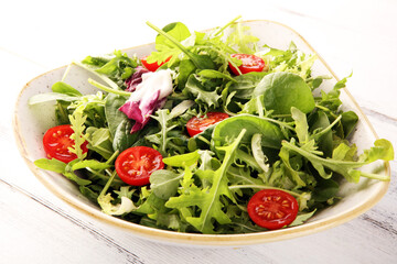 Mix fresh leaves of arugula, lettuce, spinach, beets for salad on table. Salad with tomato