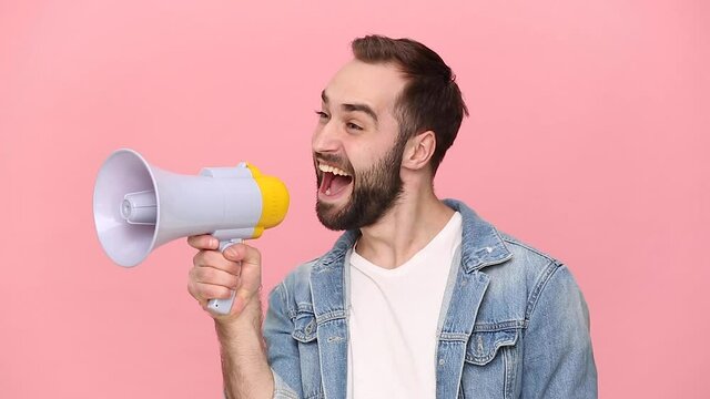 Fun young man guy 20s years old in denim jacket white t-shirt isolated on pastel pink background studio. People lifestyle concept. Looking aside scream in megaphone announces discounts sale Hurry up