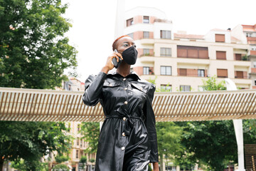 Beautiful black girl model business with mask talking on her cell phone