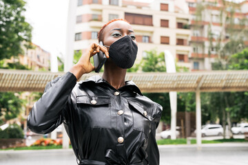 Beautiful black girl model business with mask talking on her cell phone