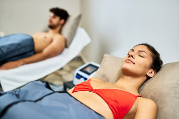 Young relaxed woman enjoying in pressotherapy at health spa.
