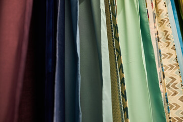 multi-colored curtains in the store. texture of multi-colored fabrics, closeup. samples of...