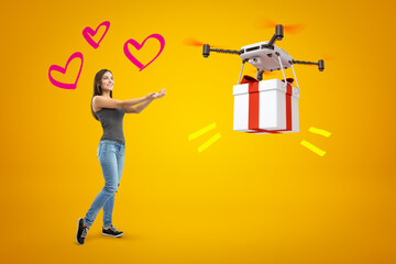Happy young girl in casual clothes and three cute hearts around head, waiting for delivery drone to drop big gift on amber background.