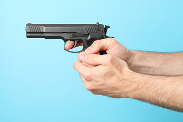 Male hands hold black pistol on blue background