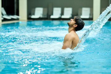 Young man enjoying in hydrotherapy at health spa.
