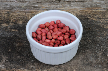Peeled peanuts in a white bowl. Front view.