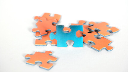 blaues Puzzel Teil vor einer Gruppe von organgen Puzzleteilen