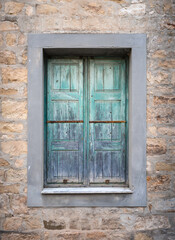 Fototapeta na wymiar Old Turquoise rural window on a stone and concrete wall