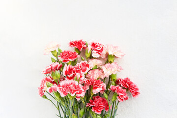 Bouquet of red and white carnation flowers on light background. Mothers day, Valentines Day, Birthday celebration concept. Copy space, top view