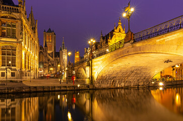 Fototapeta na wymiar The Saint Michael Bridge and the belfry tower of Gent (Ghent) with a reflection in the Leie river by the Graslei at night, East Flanders, Belgium.