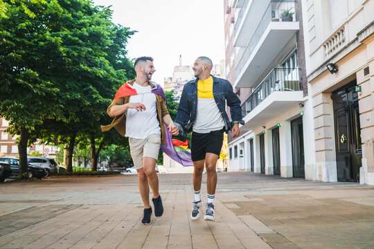 Gay couple holding their hands and running together.