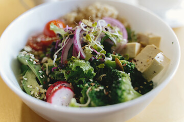Buddha bowl. Delicious vegan meal, bowl with avocado, radish, broccoli, tofu, tomato, couscous, microgreen and sesame seeds. Healthy eating concept
