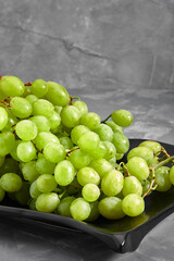 Ripe sweet white grapes. Bunch of grapes and grapes on a concrete gray background
