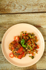 Baked chicken breast with tomatoes and vegetables garnished on a plate. Copy space.