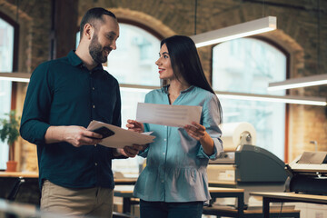 Cheerful man and woman in the office with documents in hands