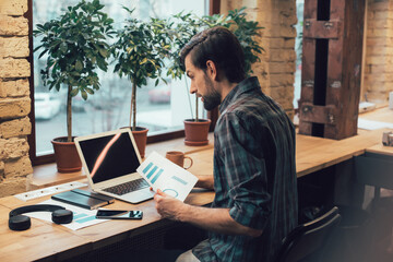 Calm man working with graphic charts in the office