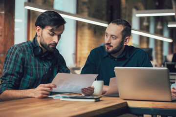 Two men at the office table discussing development of the company