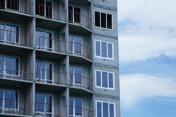 Construction of a multi-storey building close-up in residential quarter against the sky with clouds.