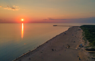 Fototapeta premium Aerial view of sunset over the sea in Palanga, Lithuania. Sandy coastline with the bridge to the sea.