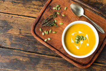 Pumpkin butternut squash cream soup in a bowl against wooden background