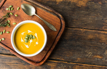 Pumpkin butternut squash cream soup in a bowl against wooden background