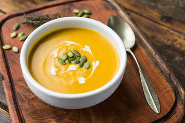 Pumpkin butternut squash cream soup in a bowl against wooden background