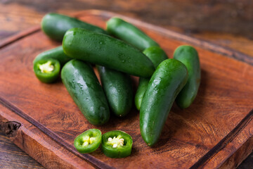 Spicy mexican jalapeno chili peppers against brown wooden background