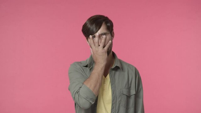 Oh god why me. Annoyed and bothered, distressed handsome man, facepalm, rolling eyes and sighing from irritation and tensed feelings, hate dealing with boring people, pink background