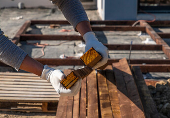 man holds a wooden beam treated with a protective layer