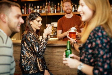 Group of friends hanging on in a pub, chatting and drinking beer.