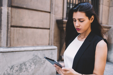 Half length portrait of latin business woman reading fashion news on her touch pad while walking on the street, modern female using digital tablet computer for navigation during walking in summer day