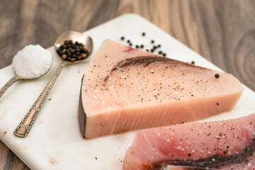 Raw swordfish. Two pieces of fresh raw fish steaks with salt and black pepper close up on marble...