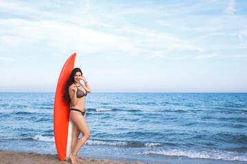 Naklejka na ściany i meble Full length portrait of a stunning female standing with surfboard against blue sea and calm sky background with copy space area for your text message or content, surfer women relaxing after swimming