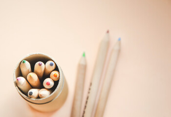 Close up picture of colorful pencils in the tube box on left side and three crayons laying on the...