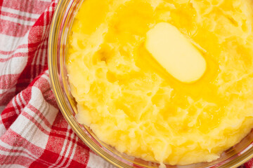 Bowl of mushed potato with melting butter close up in a glass bowl on rustic background