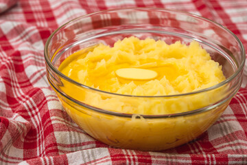 Mushed potato with melting butter close up in a glass bowl on kitchen table