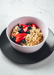 Close up view on oatmeal with strawberries and blueberries on bright textured table