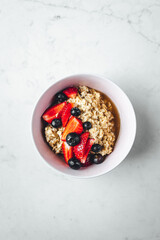 Close up view on oatmeal with strawberries and blueberries on bright textured table