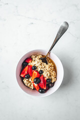 Close up view on oatmeal with strawberries and blueberries on bright textured table