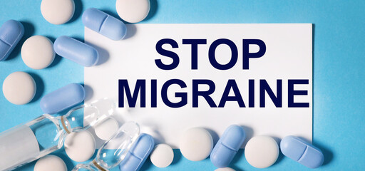 Text on a card Stop Migraine, medical concept.on a blue background with pills