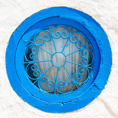 Ventana azul redonda sobre pared encalada