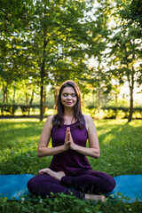 A young girl meditates on a yoga Mat in nature