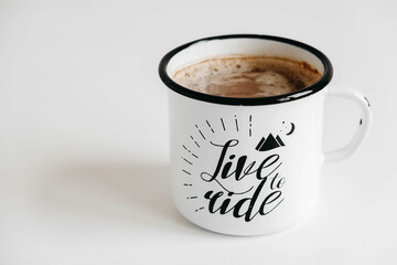 Metal mug with hot coffee on a white wooden background. Copy, empty space for text