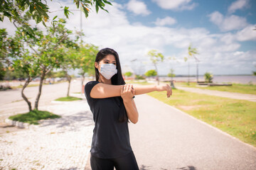 Jovem mulher se aquece e usa uma máscara para proteção.