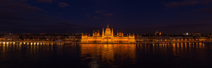 Obraz premium Panoramic aerial drone shot of Hungarian Parliament with lights on during Budapest evening