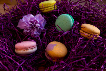 Beautiful and delicious picture. Bright colorful macaroon cakes at the background of cut purple decorative paper